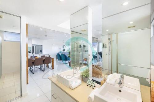 a bathroom with a sink and a mirror and a dining room at ZEN SEA BREEZE - Darwin's Premier Family Apt in Darwin