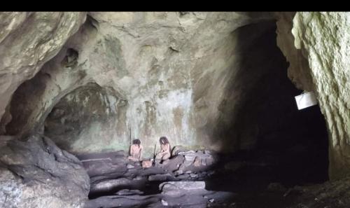 two people sitting on rocks in a cave at Къща Томови,стаи за гости in Devin