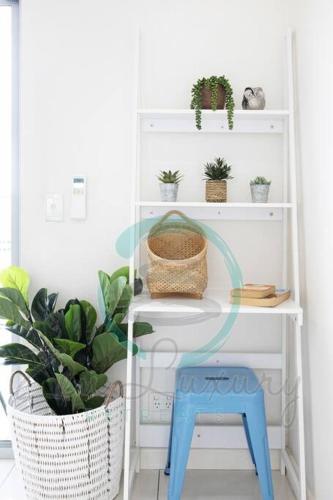 a white shelf with plants and a blue stool at ZEN SEA BREEZE - Darwin's Premier Family Apt in Darwin