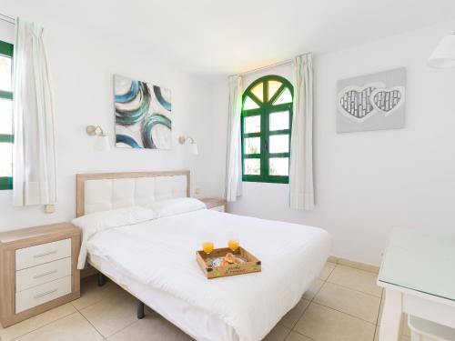 a white bedroom with two beds and a window at Marina nº 53 in Puerto de Mogán