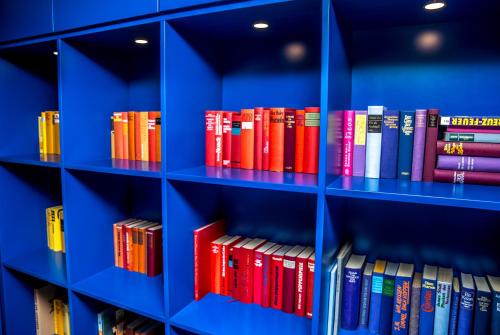a bunch of books are on blue shelves at Das Aunhamer Suite & Spa Hotel in Bad Griesbach
