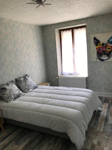 a bedroom with a large white bed with two windows at Au Faubourg in Saint-Claude