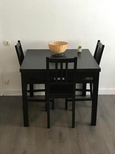 a black table with chairs and a bowl on top at Au Faubourg in Saint-Claude