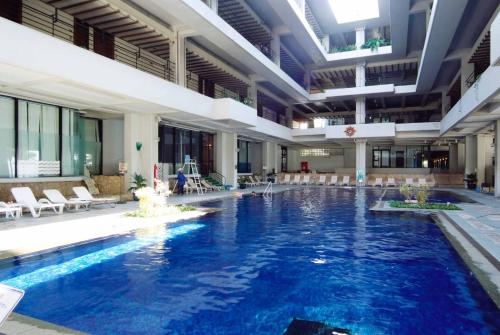a large pool in a building with chairs and tables at Palace In Moon Beach in Onna