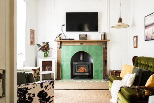 Mill Cottage في تينتيرفيلد: غرفة معيشة مع موقد وتلفزيون فوقها