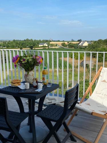 une table et des chaises sur un balcon avec une table et des fleurs dans l'établissement Appartement Lu'ermael avec vue Mont Saint Michel, à Courtils