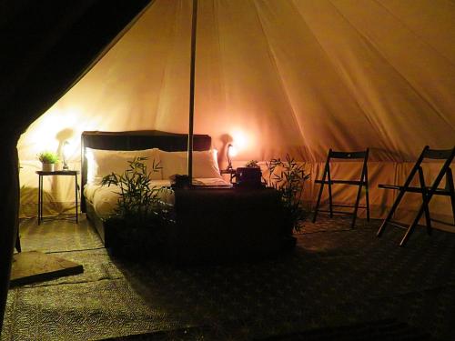 a bedroom with a tent with a bed and two chairs at Greenacres Glamping in Lea