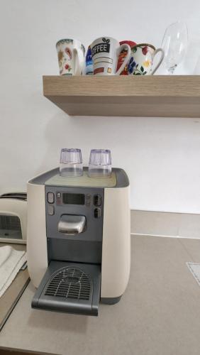 a coffee maker on a counter with cups on a shelf at יחידת דיור in Rishon LeẔiyyon