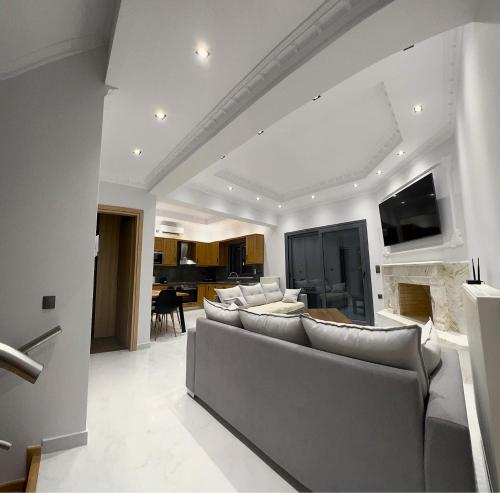 een woonkamer met een bank en een tv aan de muur bij KONTIS' Deluxe furnished apartment in Loutraki