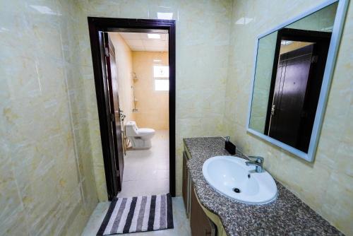 uma casa de banho com um lavatório, um espelho e um WC. em نسائم صلاله NassayemSalalah em Salalah