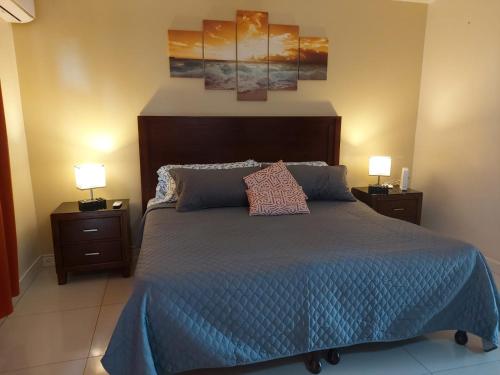 a bedroom with a bed with a blue bedspread and two lamps at Deluxe SandCastles Condos in Ocho Rios