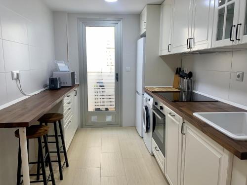 eine Küche mit weißen Schränken und einer Arbeitsplatte in der Unterkunft Precioso apartamento primera línea de playa in Águilas