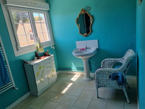 a blue bathroom with a sink and a chair at Angèle in Audinghen