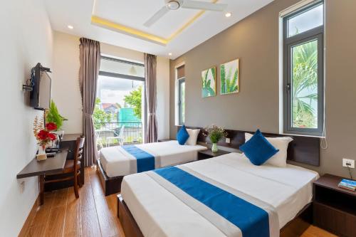 a hotel room with two beds and a window at Villa Charming Hoi An in Hoi An