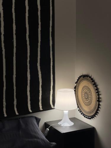 a lamp on a nightstand next to a black and white blanket at شقة خاصة بتصميم مختلفة وجميل في موقع ممتازEntire apartment in Al Ahsa