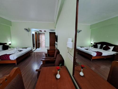 a hotel room with two beds and a mirror at Hotel Preethi Classic Towers in Ooty