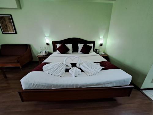 a bedroom with a bed with two teddy bears on it at Hotel Preethi Classic Towers in Ooty