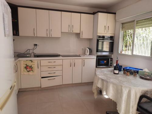 a kitchen with white cabinets and a table with wine bottles on it at Best Home Jerusalem Holy Land Close to Everything Israel Gateway 4 families & individual in Jerusalem