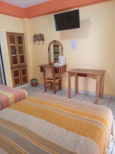 Cette chambre comprend deux lits, un bureau et une télévision. dans l'établissement El Tucan, à Puerto Escondido