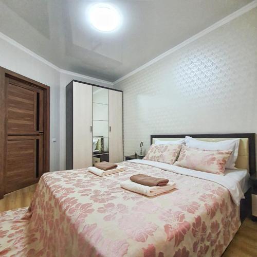 um quarto com uma cama grande com duas toalhas em Уютная квартира в г.Алматы em Almaty