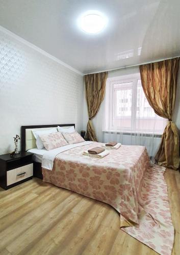 um quarto com uma cama grande e uma janela em Уютная квартира в г.Алматы em Almaty