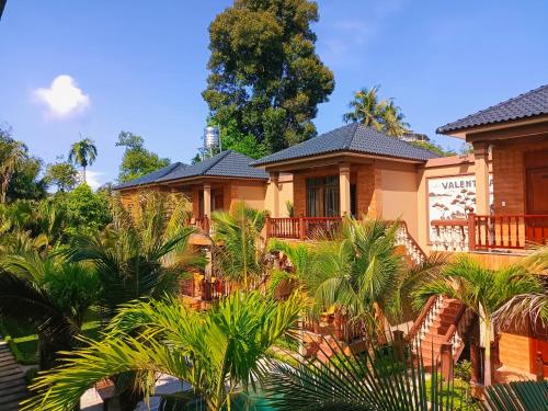 a house with palm trees in front of it at Valentina Resort & Spa Phu Quoc in Phu Quoc