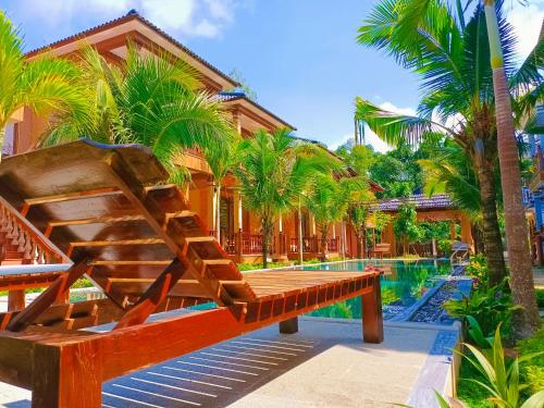 a wooden bench next to a swimming pool with palm trees at Valentina Resort & Spa Phu Quoc in Phu Quoc