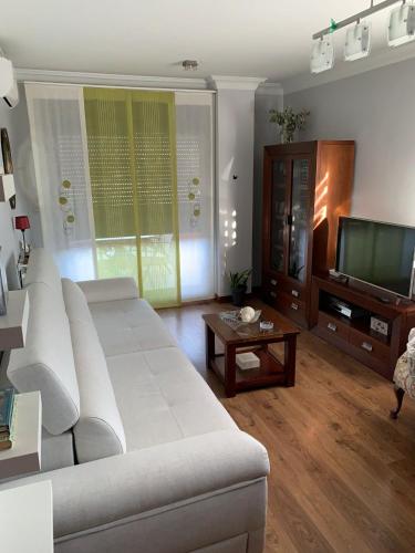 a living room with a white couch and a television at Ático gran manzana granada in Granada