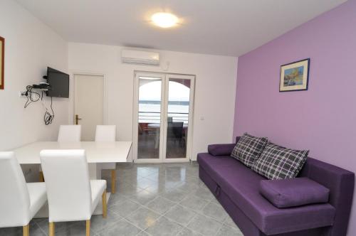 sala de estar con sofá púrpura y mesa en Apartments Marija - Maslenica en Maslenica