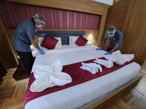 two men are preparing a bed in a hotel room at Hotel Preethi Classic Towers in Ooty