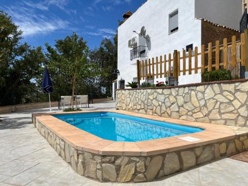 una piscina con un muro di pietra accanto a una casa di Villa Río Béjar a Quesada