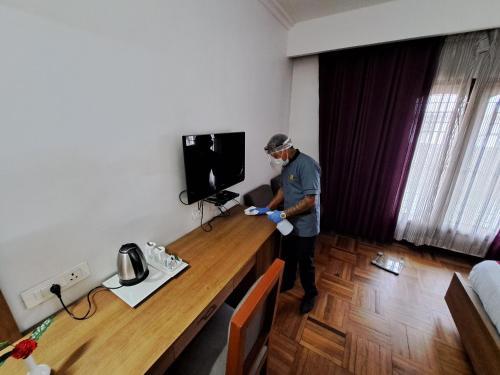 a man is standing in a room with a desk at Hotel Preethi Classic Towers in Ooty