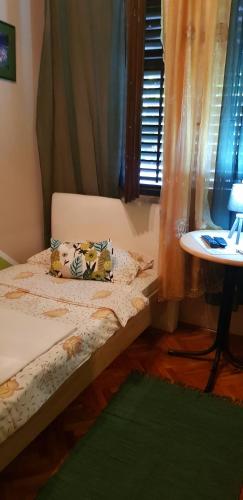 a bed in a room with a table and a window at Guest House Cinderella in Herceg-Novi