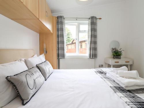 a bedroom with a large white bed with a window at Honeysuckle Lodge in Windermere