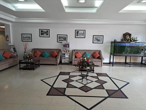 a living room with couches and a table on a tile floor at Hotel Preethi Classic Towers in Ooty