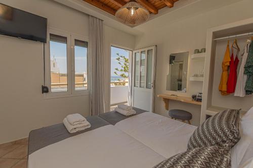 1 dormitorio con 1 cama blanca grande y escritorio en Naxian City Rooms, en Naxos Chora