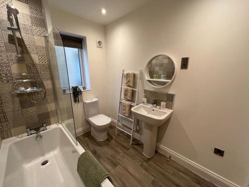 a bathroom with a tub and a sink and a toilet at DAIRY COTTAGE WHITBY in Whitby