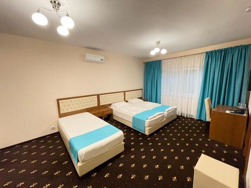 a hotel room with two beds and a desk at Hostel Paltinis in Hunedoara