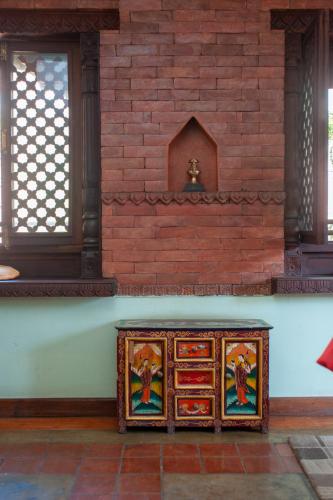 a wooden cabinet with paintings on it next to a brick wall at New Orleans Apartment in Kathmandu