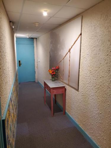 a hallway with a table and a blue door at Le Richelieu in Le Boulou
