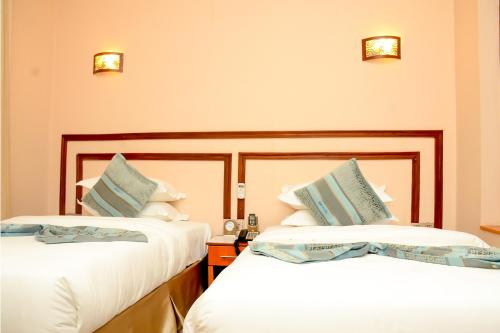 2 letti in camera d'albergo con lenzuola bianche di Kim Hotel a Kigali