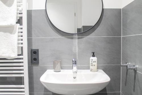 a white sink in a bathroom with a mirror at New York Apartment - für Freunde & Familien, stadtnah, Parkplatz, E-Ladestation, Gitterbox für Fahrräder, Fitnessstudio, digitale Gästemappe mit Restaurant- und Unternehmenstipps in Koblenz