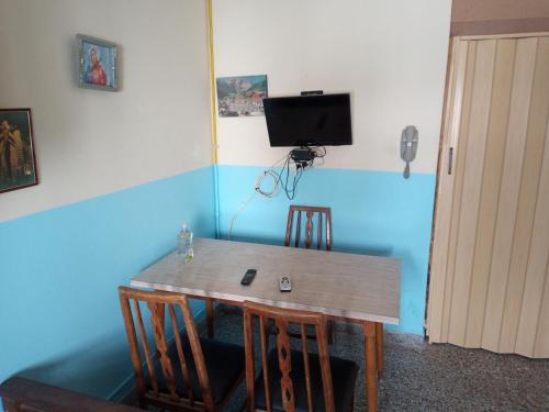 a dining room table with chairs and a television on the wall at Departamento 1 ambiente 3 personas a metros del mar in Mar de Ajó
