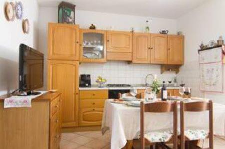 eine Küche mit Holzschränken und einem Tisch mit einem TV in der Unterkunft CASA IRIDE in Castiglion Fiorentino