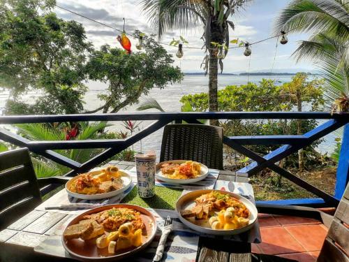 a table with three plates of food on a balcony at Mosana Reef Garden B&B in Bocas del Toro