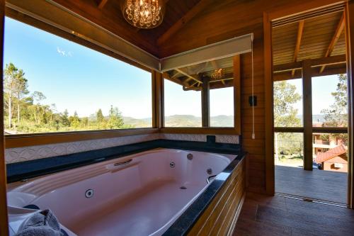 uma grande banheira num quarto com janelas em Stillo Gramado Linha Bonita em Gramado