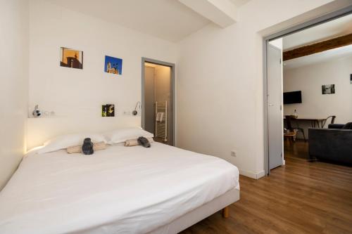 une chambre avec un grand lit blanc et un salon dans l'établissement Les appartements quartier San Carlu, vieille ville & Citadelle, à Ajaccio