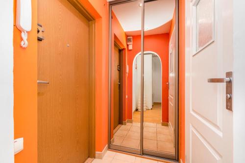 a hallway with orange walls and a mirror at Anielewicza 49 by Homeprime in Warsaw
