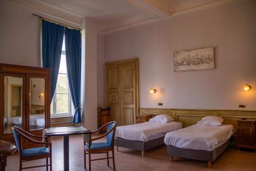 a bedroom with two beds and a table and chairs at Domaine Du Chateau De La Neuville in Tihange