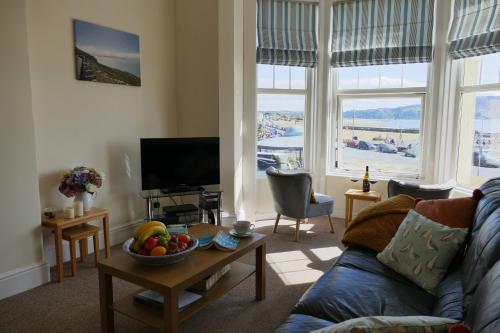a living room with a couch and a table with a bowl of fruit at ShellSeekers Holiday Apartment, Llandudno in Llandudno